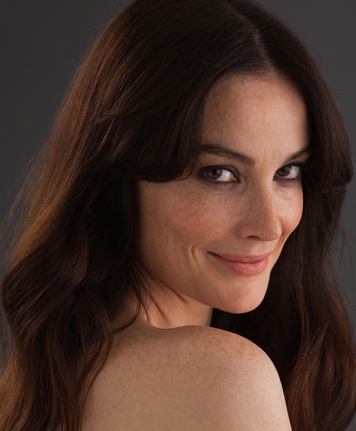 Smiling woman with long, wavy brown hair.