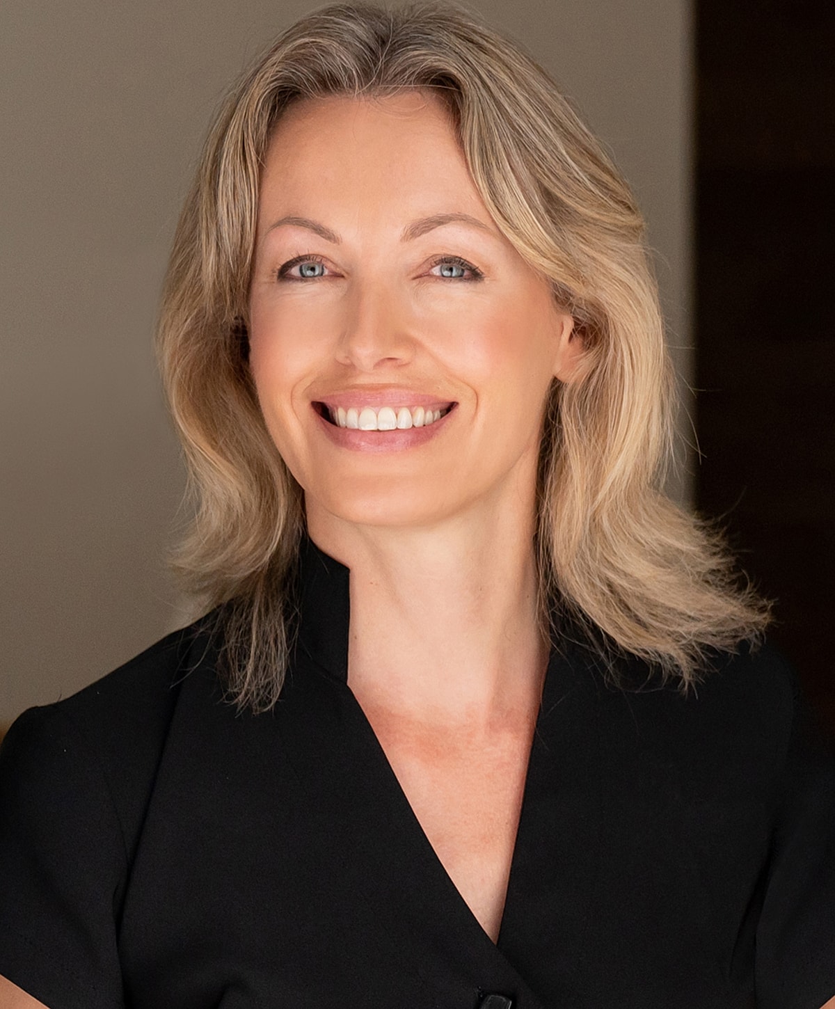 Smiling woman with long hair, natural light.