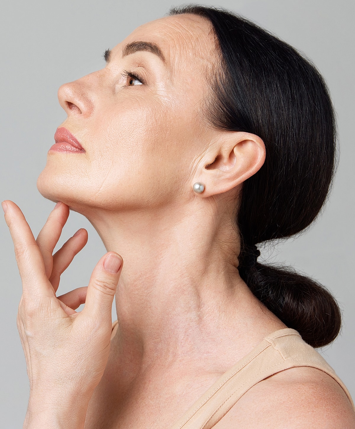 Woman with elegant hairstyle touching her chin.
