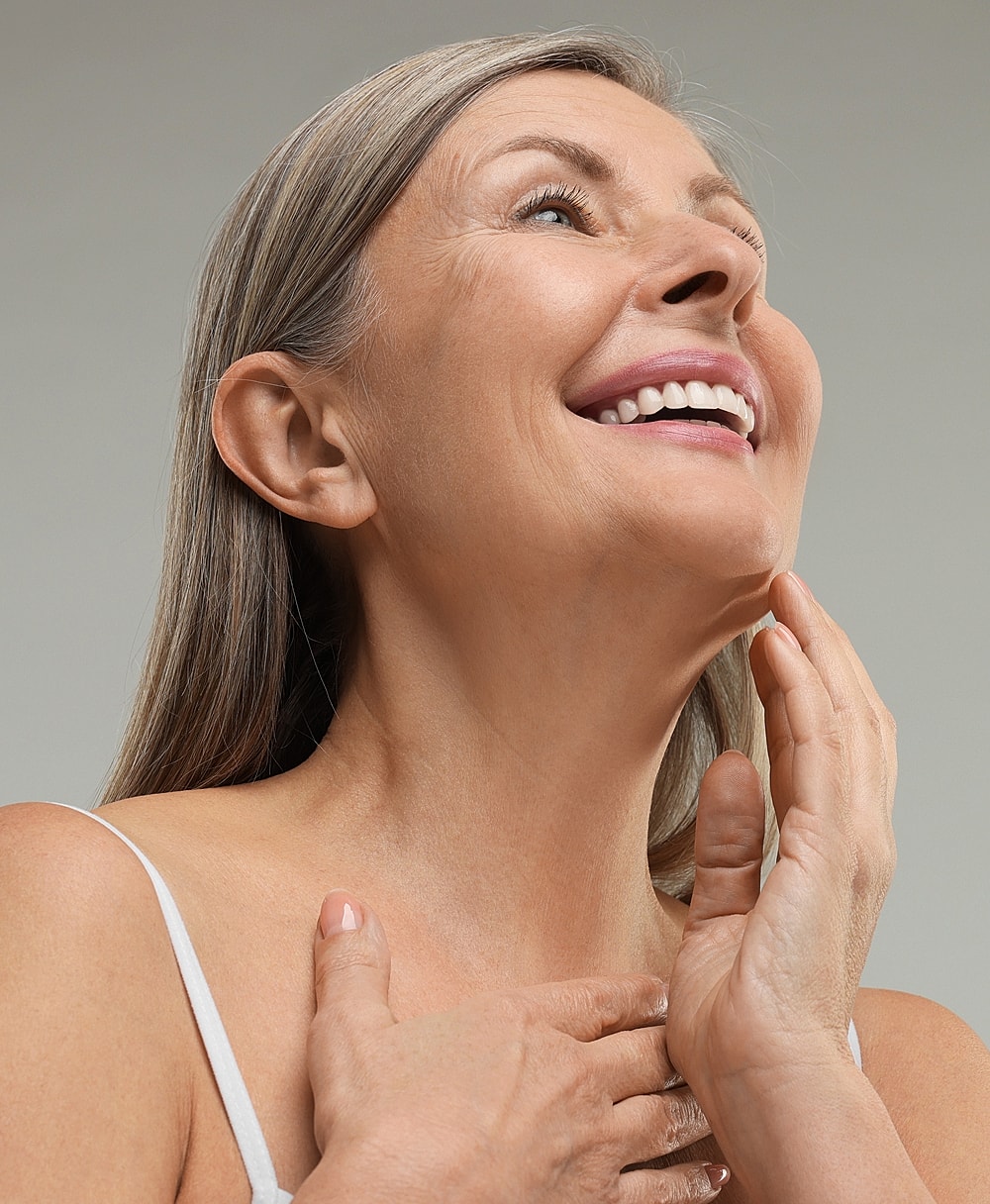 Smiling woman touching her neck and chin.