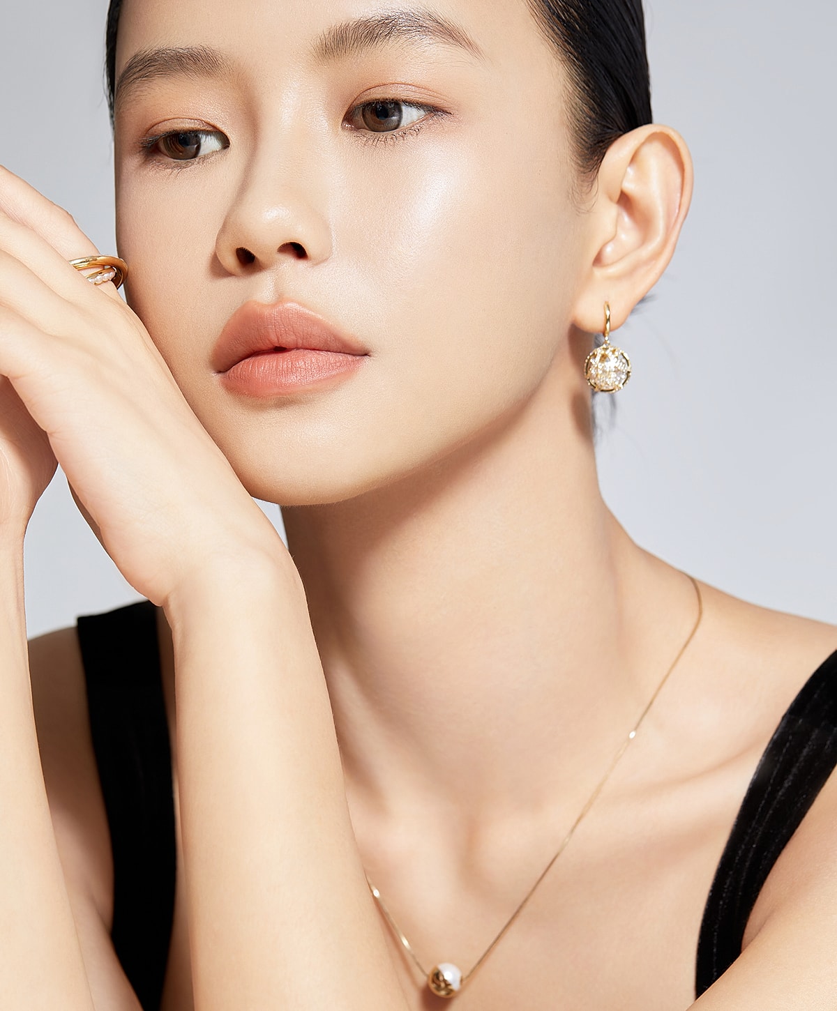 Elegant woman with gold jewelry and natural makeup.
