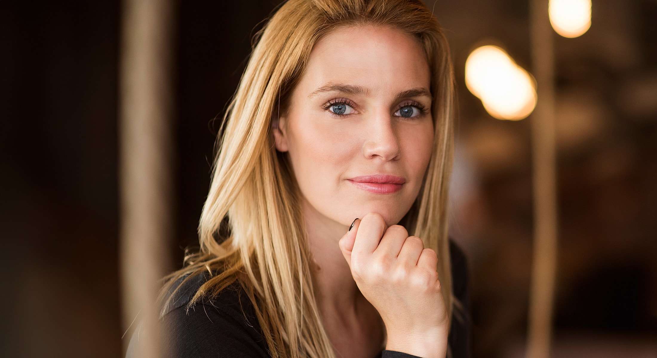 Woman showcasing jewelry and natural makeup look.