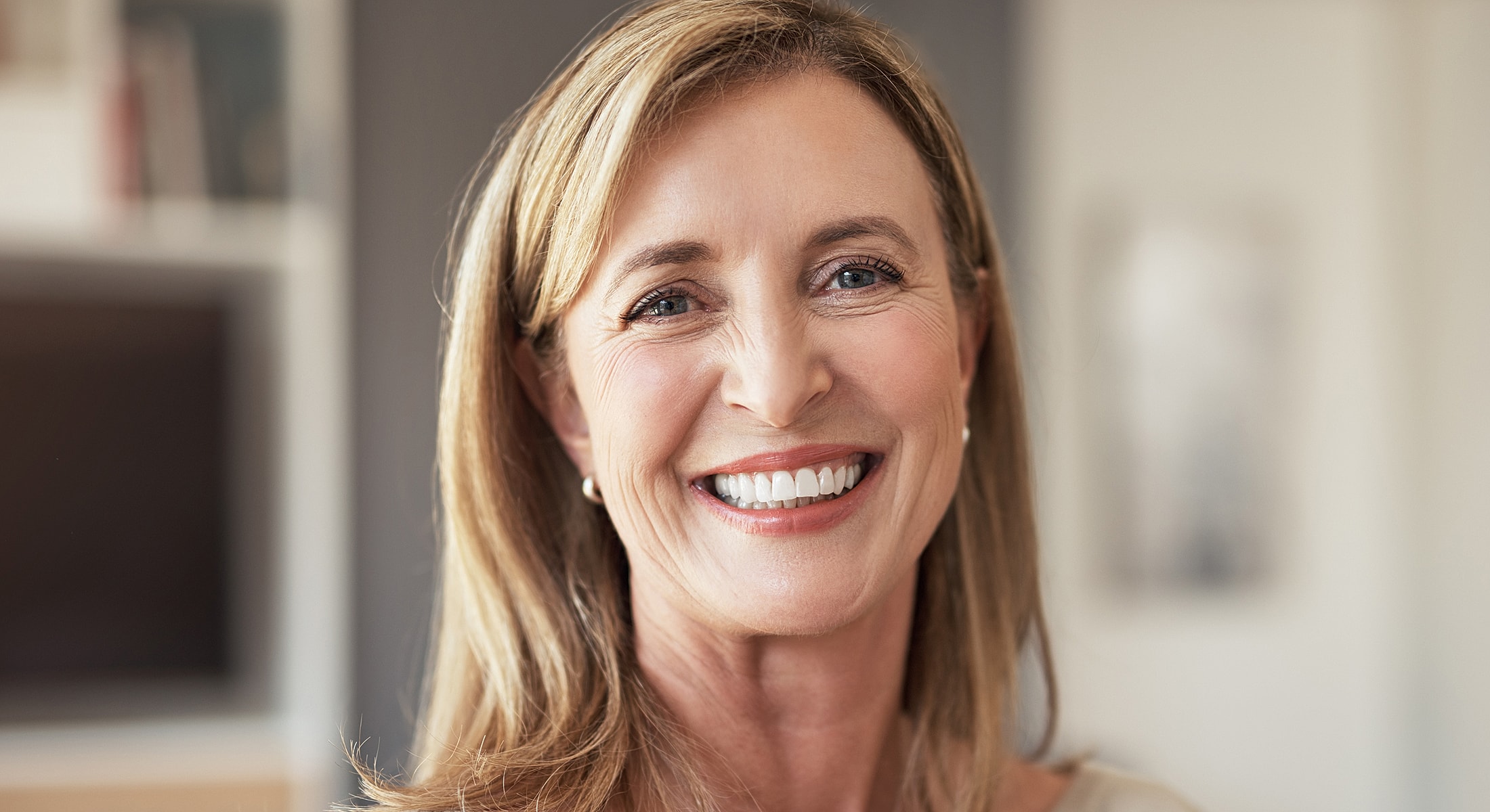 Smiling woman with blonde hair in casual setting.