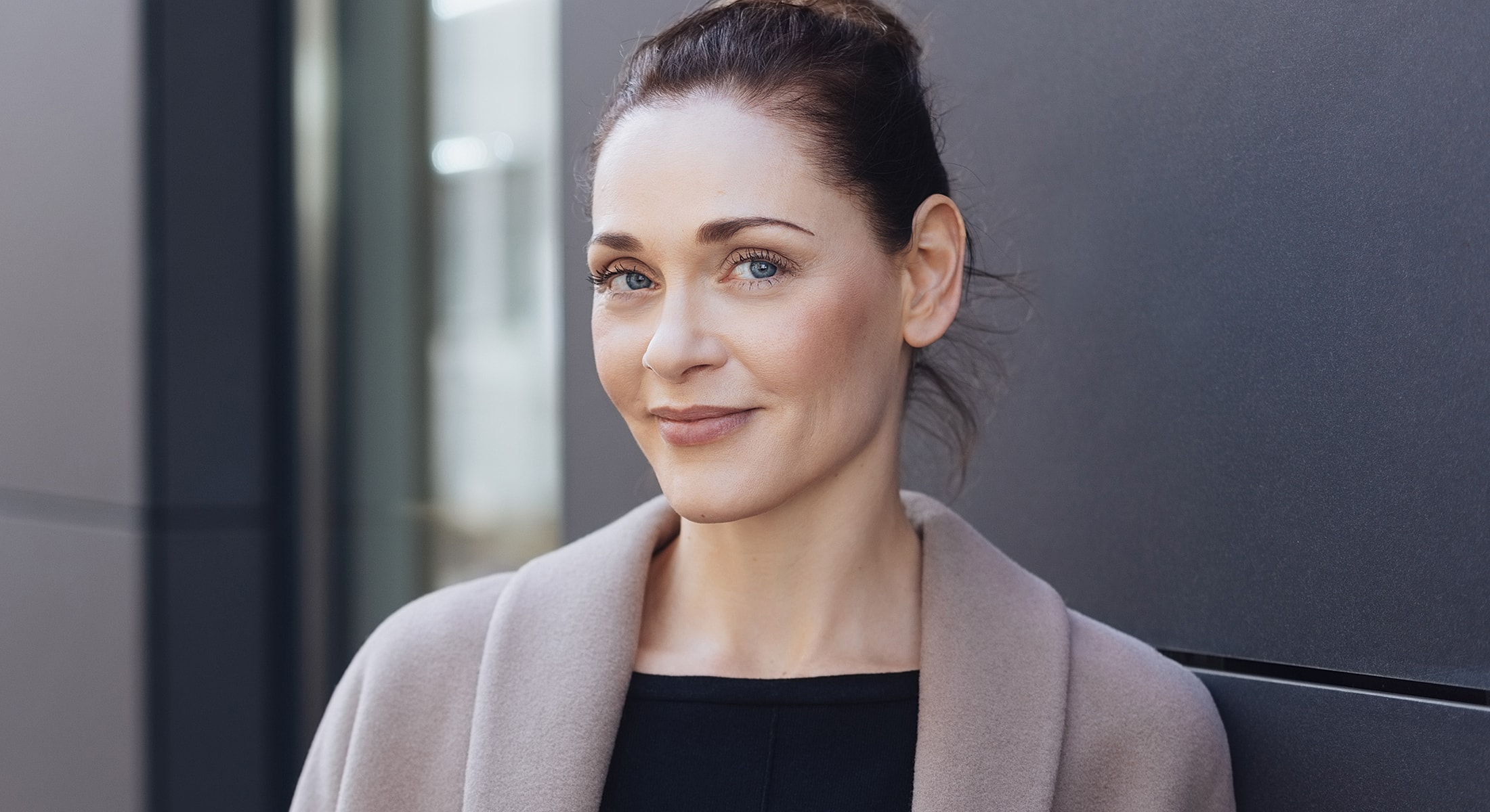 Woman smiling against a dark background.