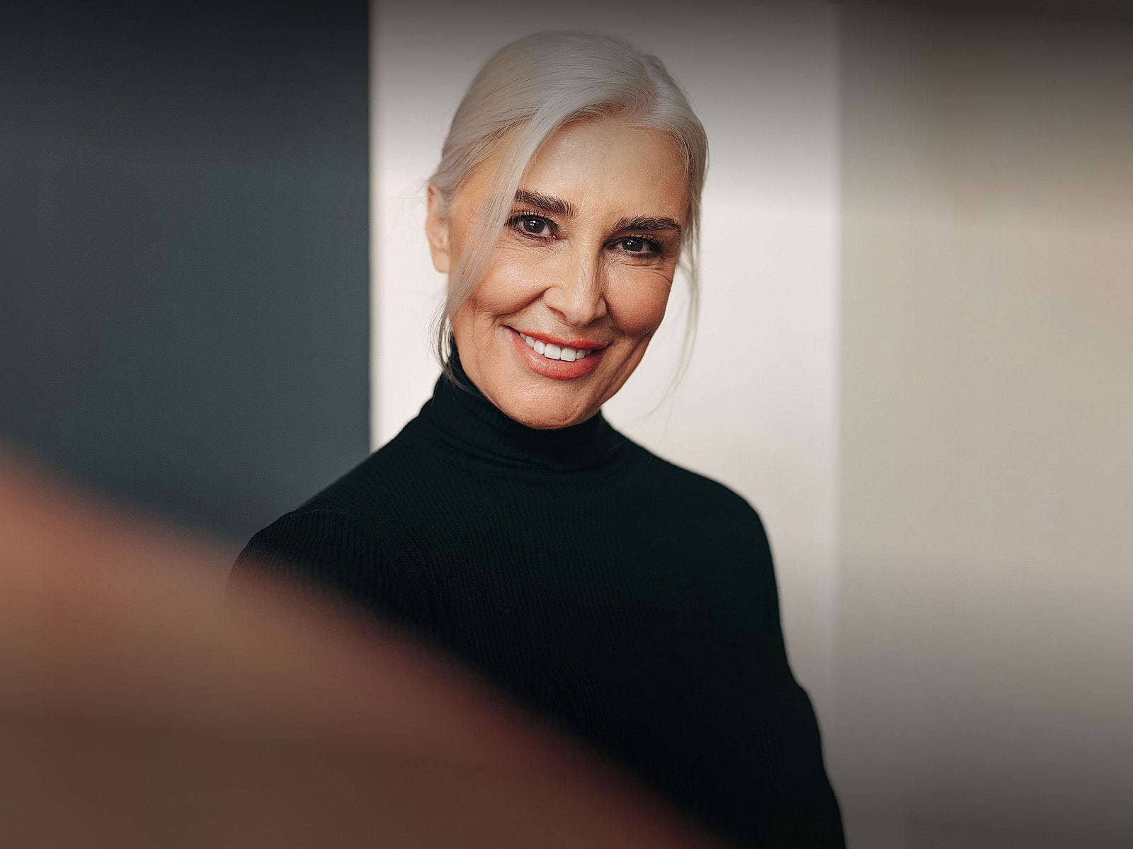 Smiling older woman in a black turtleneck.