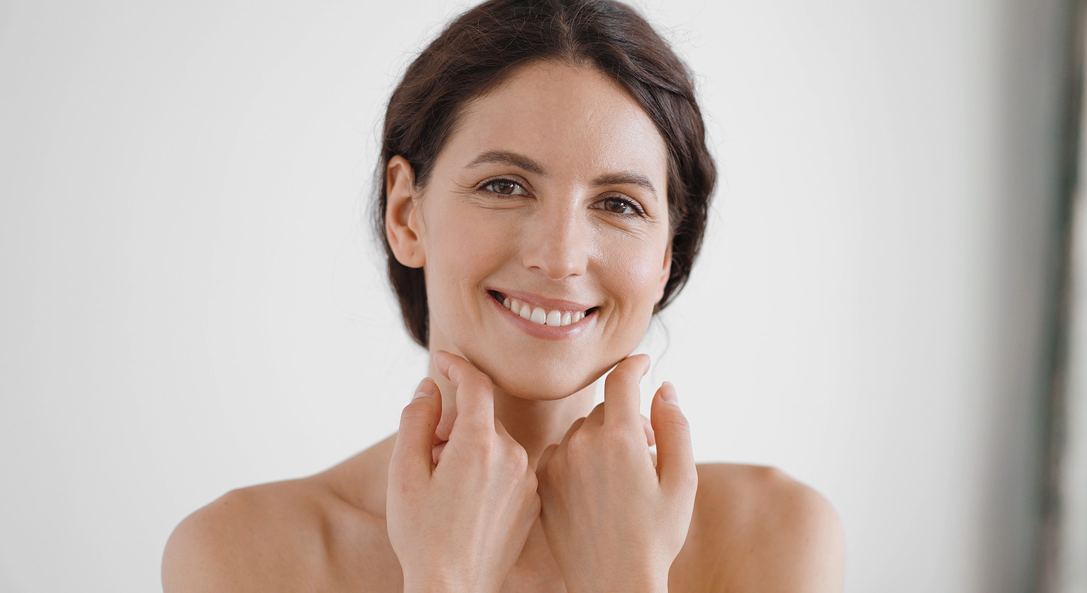 Smiling woman touching her chin and neck.
